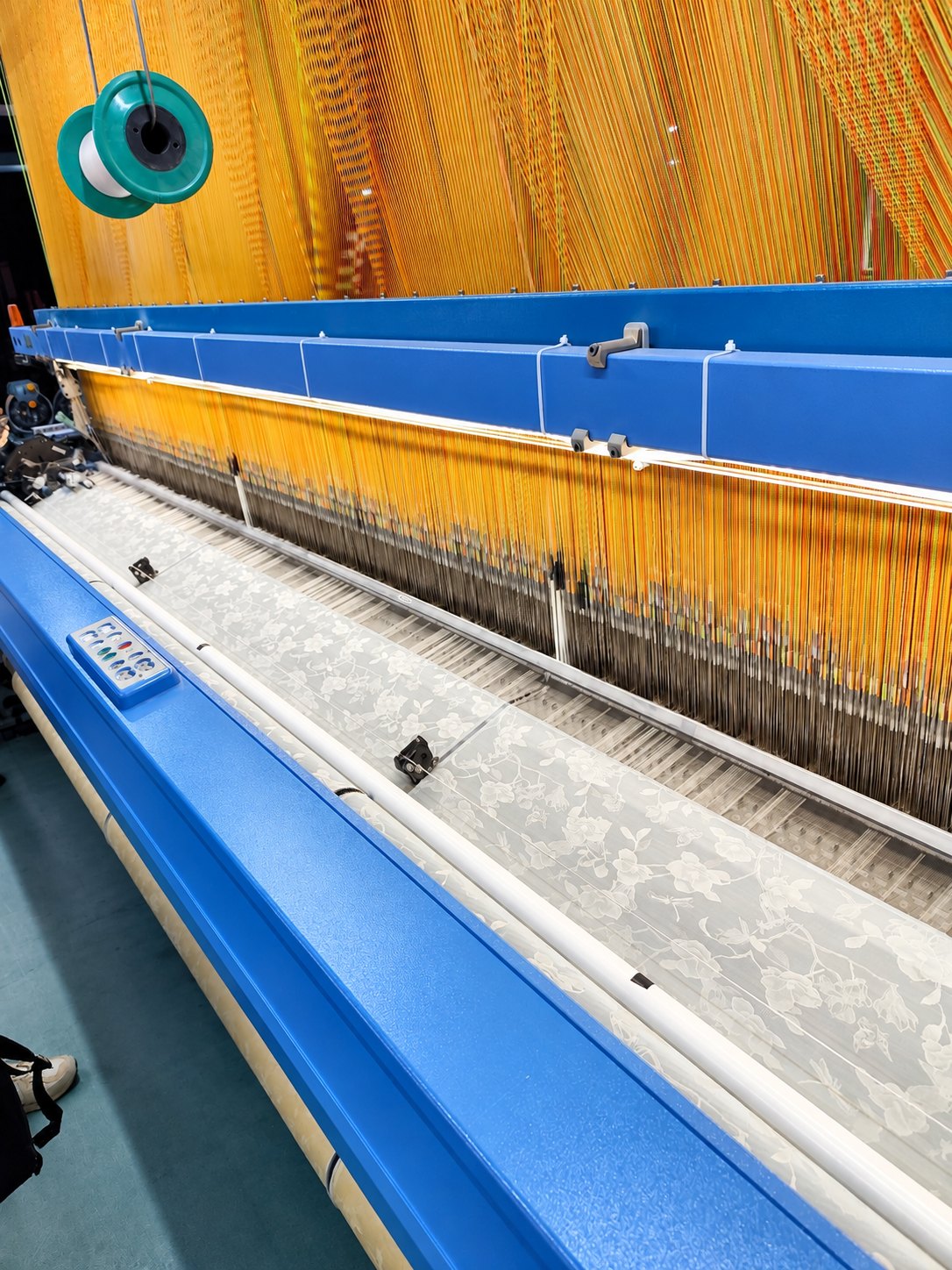 Patterned fabric being formed on textile weaving equipment in China